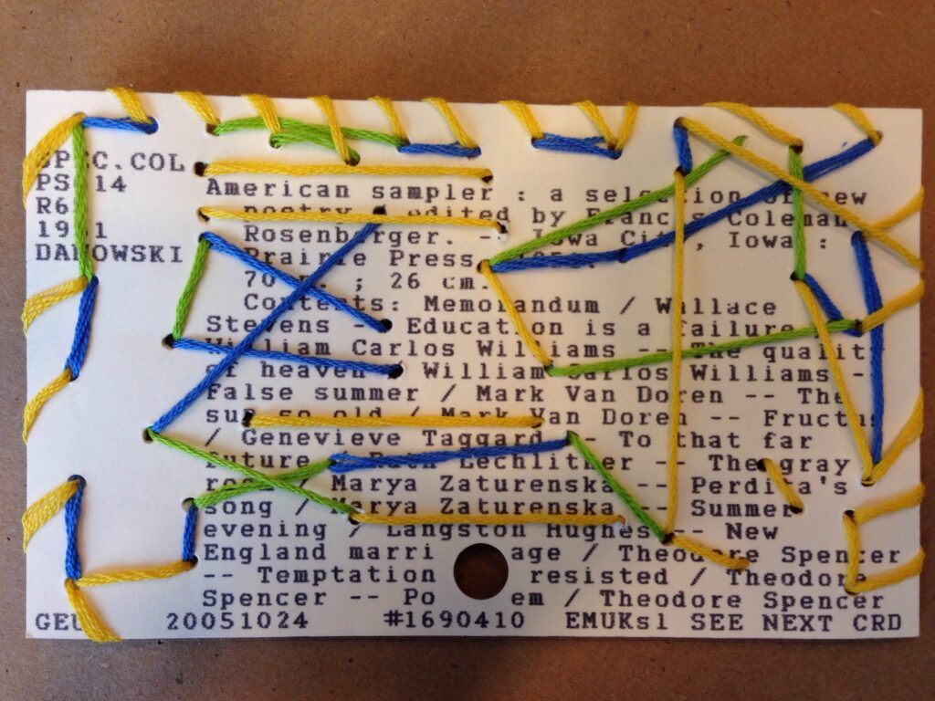 Card catalog card sewn in a random pattern with green, blue, and yellow embroidery thread.