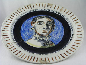 Painted plate with a portrait of a woman in the center of the plate.