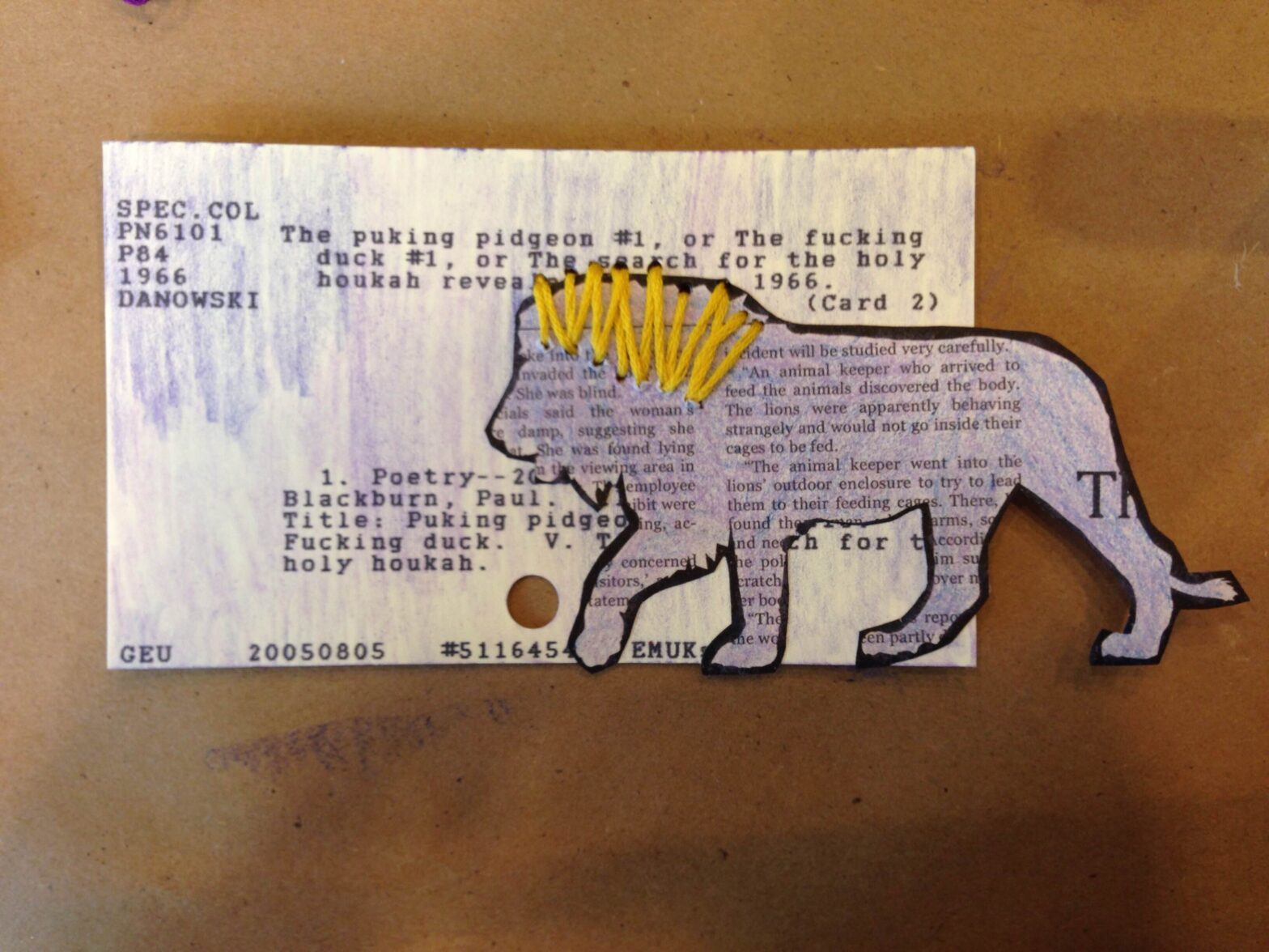 Card catalog decorated with shades of purple colored pencil, a cutout lion with a sewn yellow embroidery thread mane.